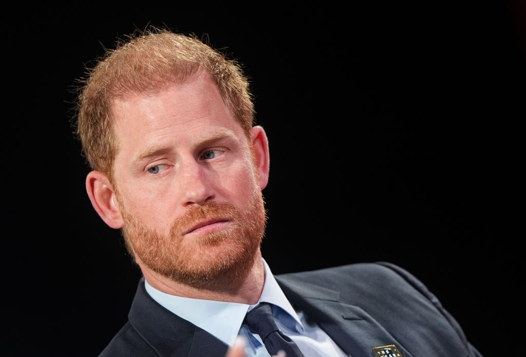 Prince Harry in black suit looking stern