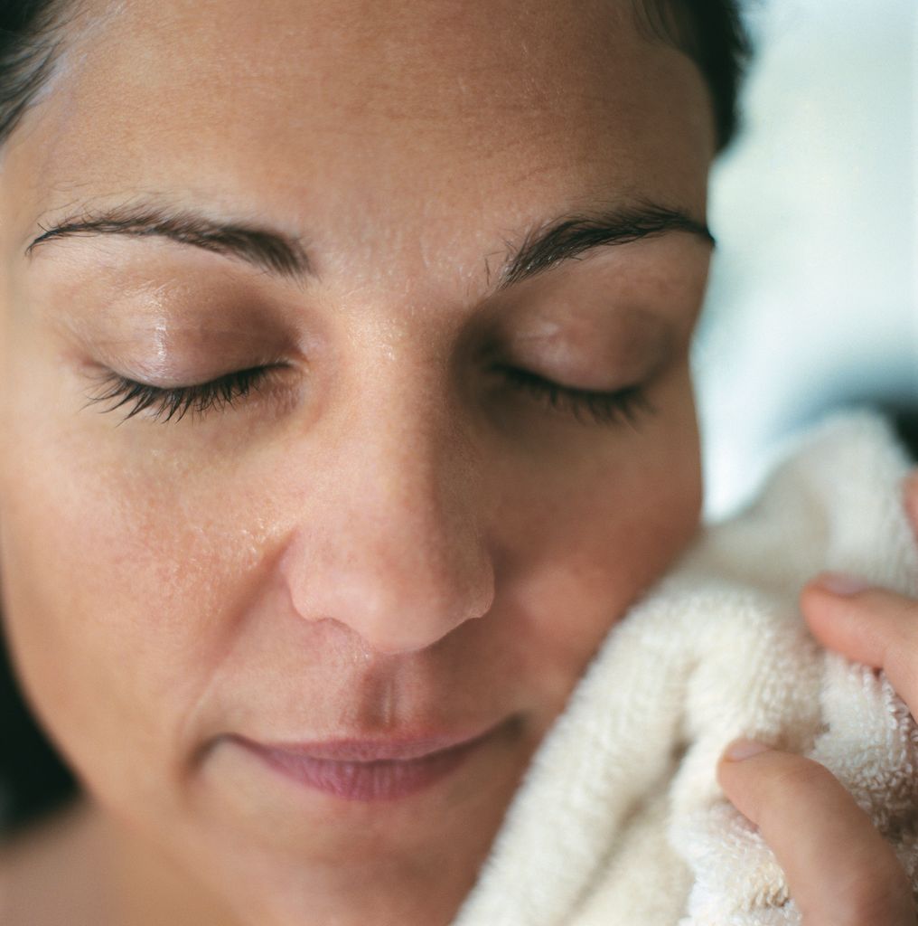 woman holding wash cloth to face