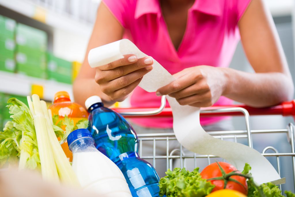 Woman checking expensive food shop bill in supermarket