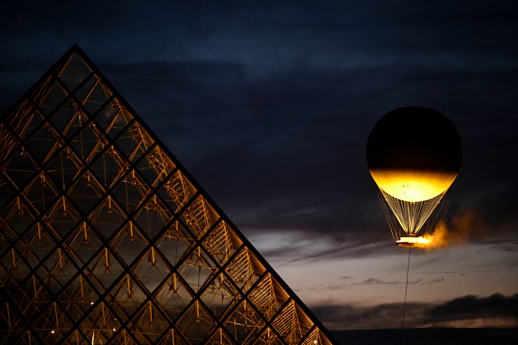 This photograph shows the Paris 2024 Olympic Games cauldron attached to a balloon overlooking the Louvres glass pyramid designed by Chinese-US architect Ieoh Ming Pei in Paris on August 6, 2024. 