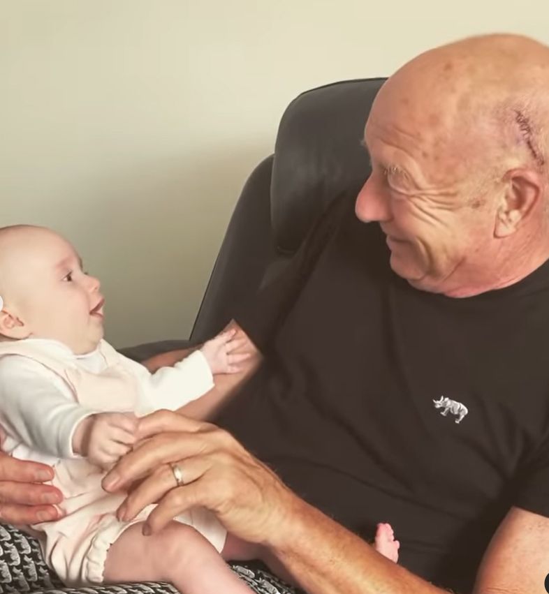 Elderly man tickling his granddaughter