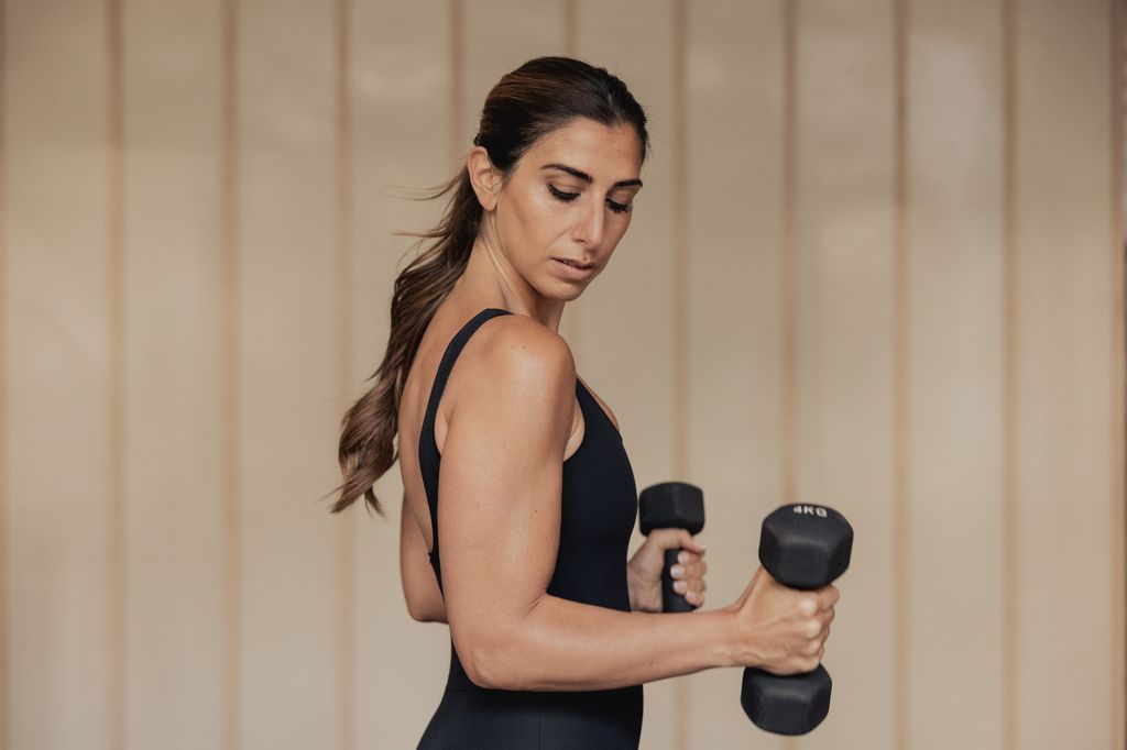 Woman flexing while holding dumbells 