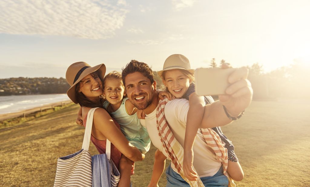 Shot of a father taking a selfie with his family while out on the beach 