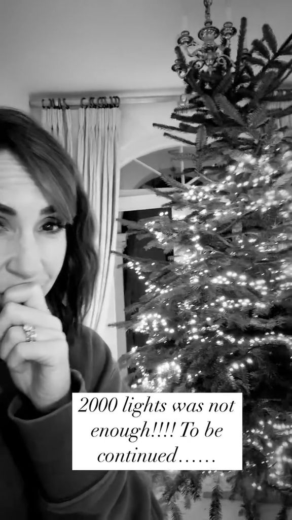 Alex Jones with her hand to her face against the backdrop of her Christmas tree