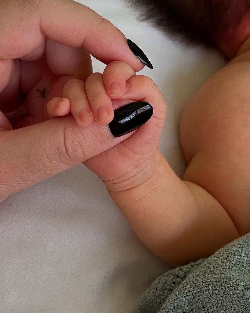 woman holding hands with a tiny baby