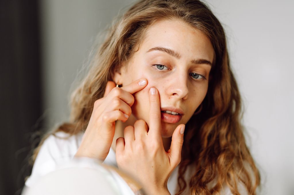 woman squeezing spot pimple milia on face.