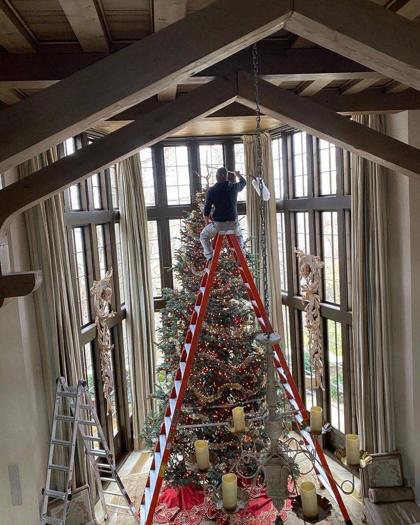 Tim decorated the Christmas tree inside a huge living area with beamed ceilings and large windows