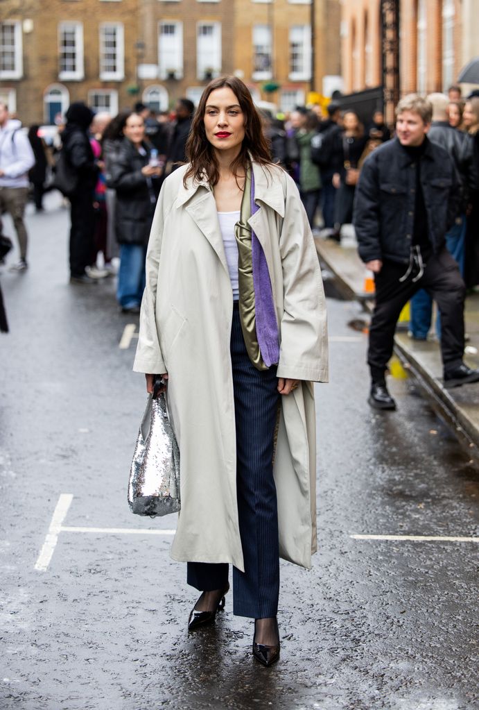 LONDON, ENGLAND - FEBRUARY 18: Alexa Chung wears trench coat, silver sequined bag, blue striped pants outside JW Anderson during London Fashion Week February 2024 on February 18, 2024 in London, England. (Photo by Christian Vierig/Getty Images)