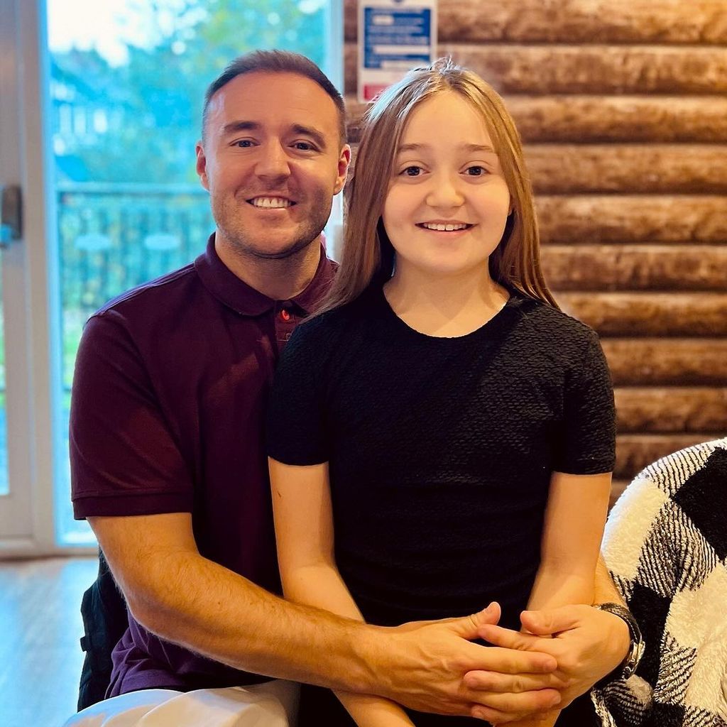 Alan Halsall wears a burgundy polo shirt and smiles with his daughter Sienna