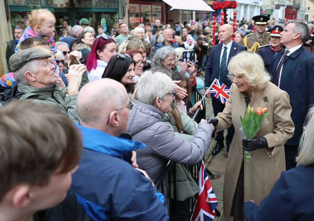 Queen Camilla shakes hands with a well-wisher during her visit to The Poppy Project