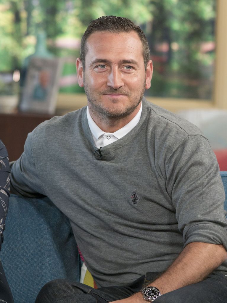 man in grey jumper sitting on sofa in tv studio