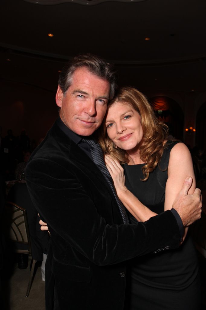 Pierce Brosnan tient son bras autour de René Russo tandis qu'elle tient une main sur sa poitrine.