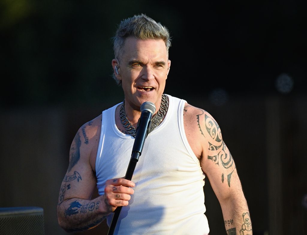 Robbie Williams performing in a white tank top