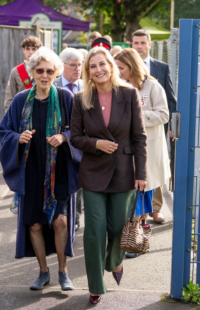 Sophie carrying a zebra print bag walking next to lady