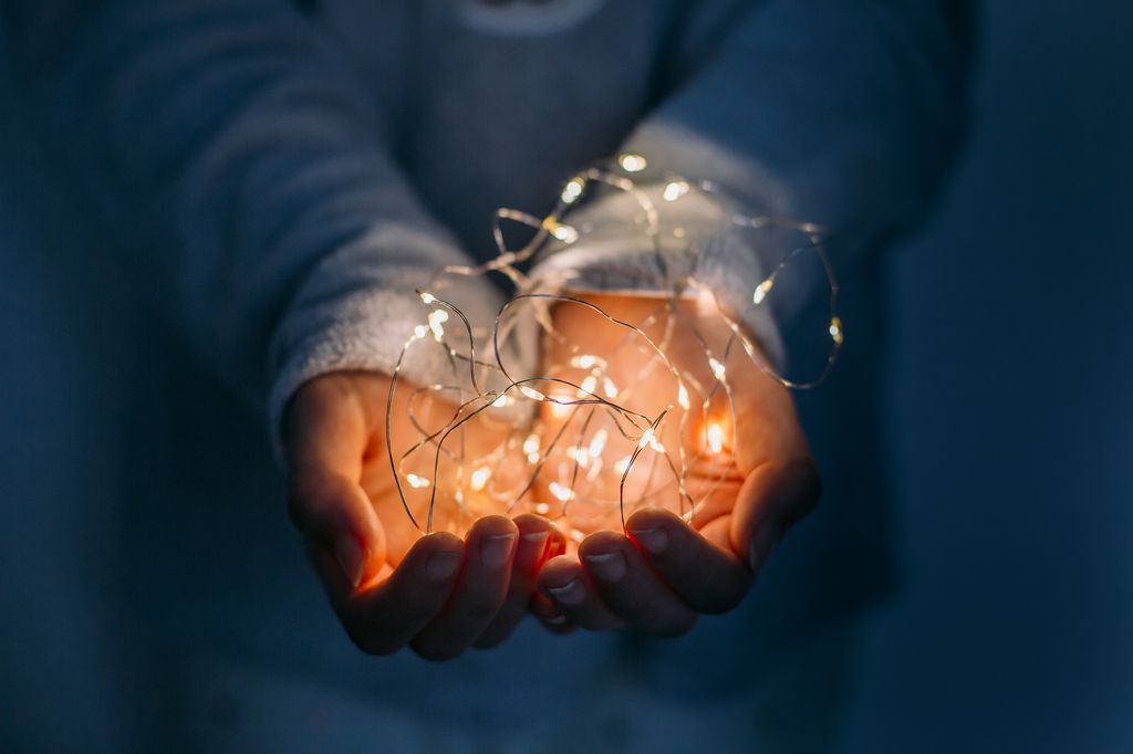 A woman clasps a string of fairy lights