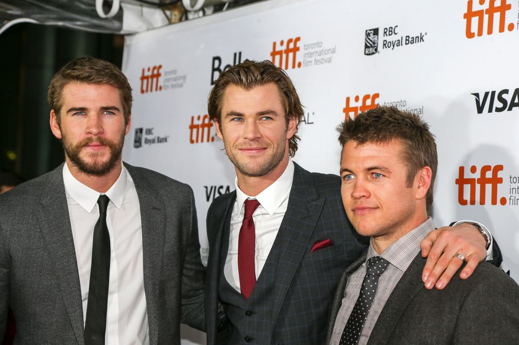 Liam Hemsworth, Chris Hemsworth and Luke Hemsworth all standing in suits