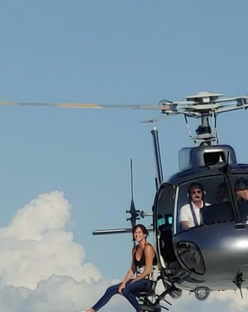 Photo shared by Charlize Theron sitting on the edge of a helicopter while filming The Old Guard 2