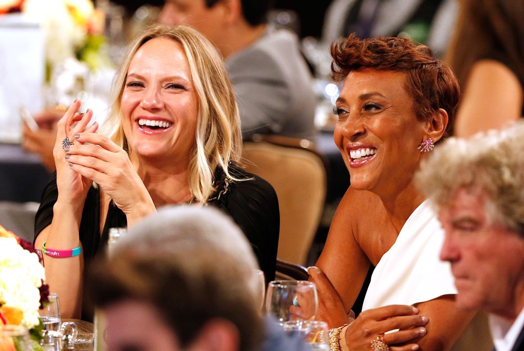 Robin Roberts and Amber Laign smiling sat at a table during an event