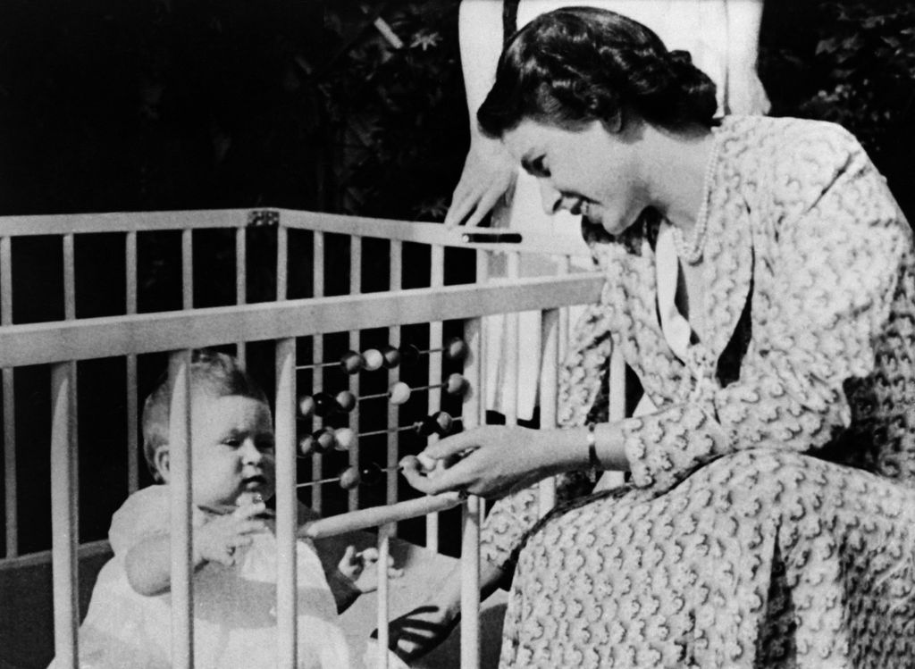 Queen Elizabeth II of England with her baby Charles in the crib