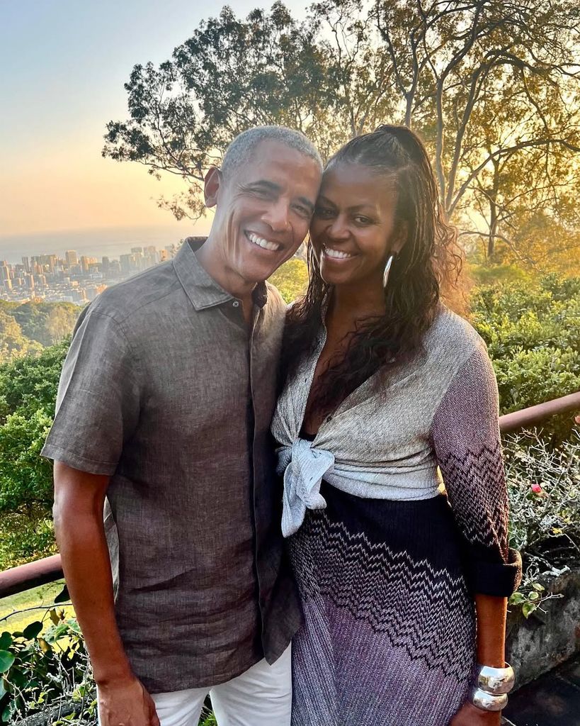 Barack and Michelle Obama smiling for a photo in front of scenic view