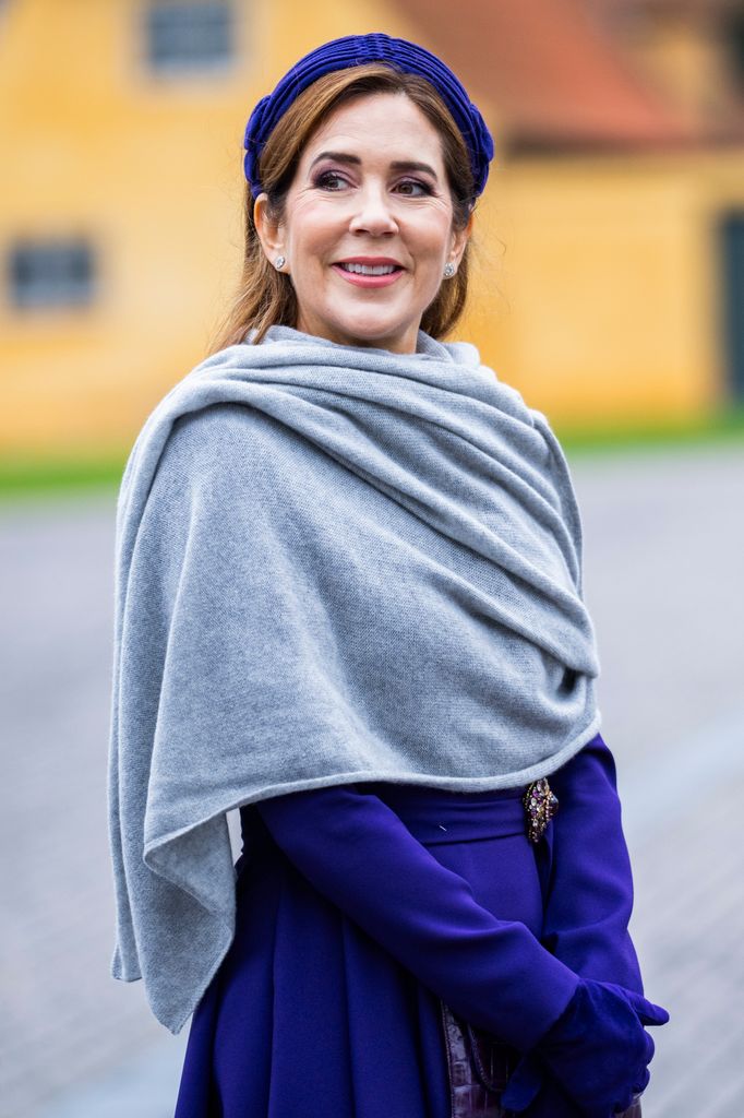 Queen Mary in purple dress and headband with grey shawl