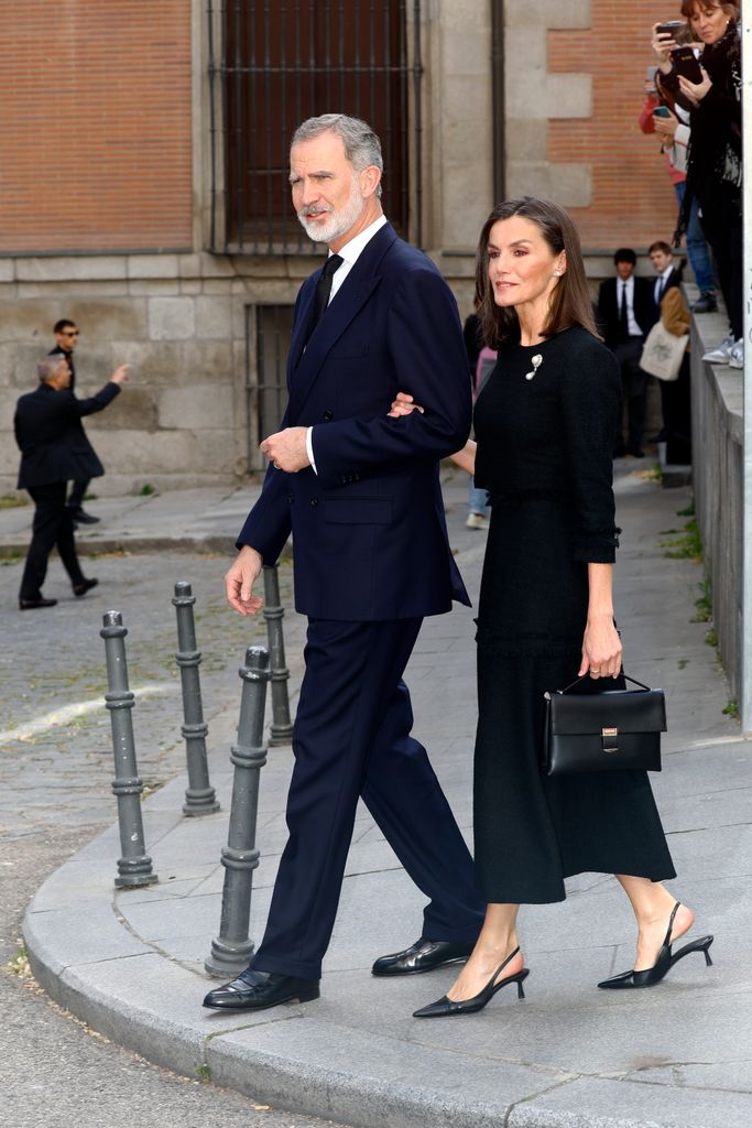 Queen Letizia walking arm in arm with felipe in black