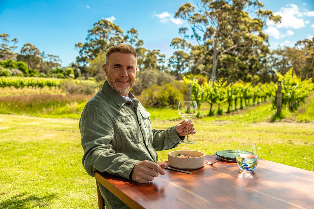 man holding glass of wine in wineyard