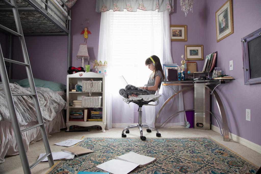 Young girl being homeschooled studying through technology at home