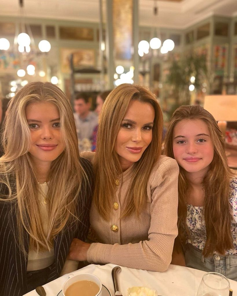 Amanda smiling alongside her two daughters