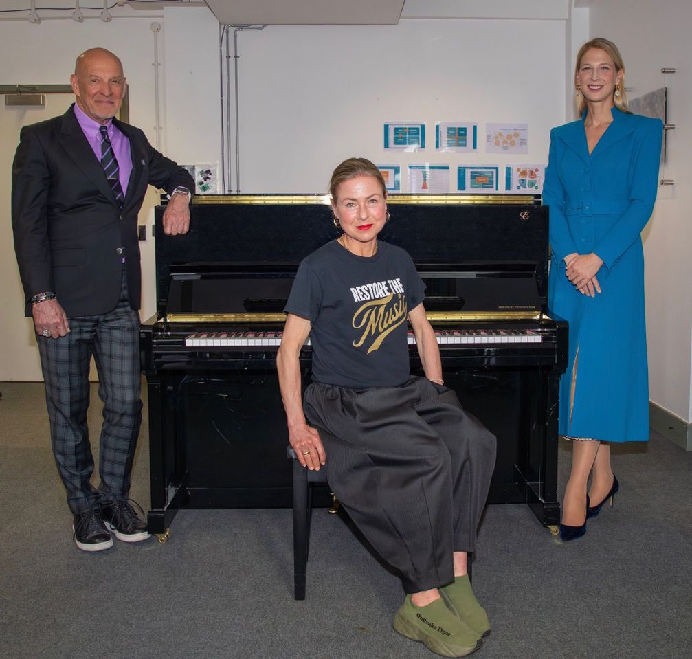 Three people posing in front of a piano