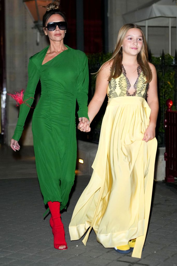 Victoria Beckham in a green dress holding hands with Harper Beckham