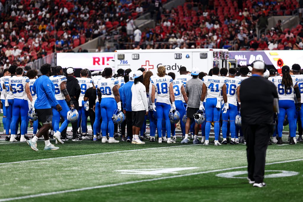 Detroit Lions players huddle around an ambulance after Morice Norris #26 sustained an injury 