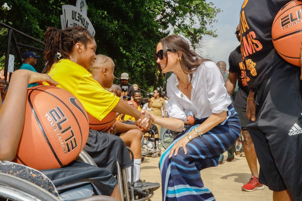 Meghan Markle holding hands with child during Giants of Africa at Ilupeju Senior Grammar School o