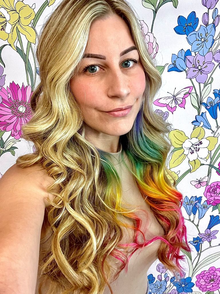 blonde lady in front of floral wallpaper