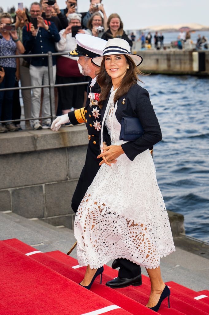 King Frederik X of Denmark and Queen Mary in white dress walking up steps