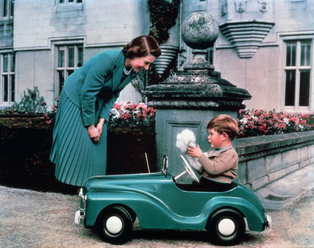 Queen Elizabeth watches her son Prince Charles driving in a toy car on the grounds of Balmoral Castle. (Photo by © Hulton-Deutsch Collection/CORBIS/Corbis via Getty Images)