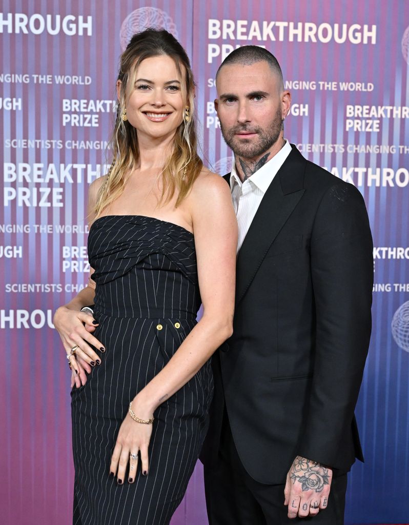 Adam Levine with his arm around a smiling Behati Prinsloo 