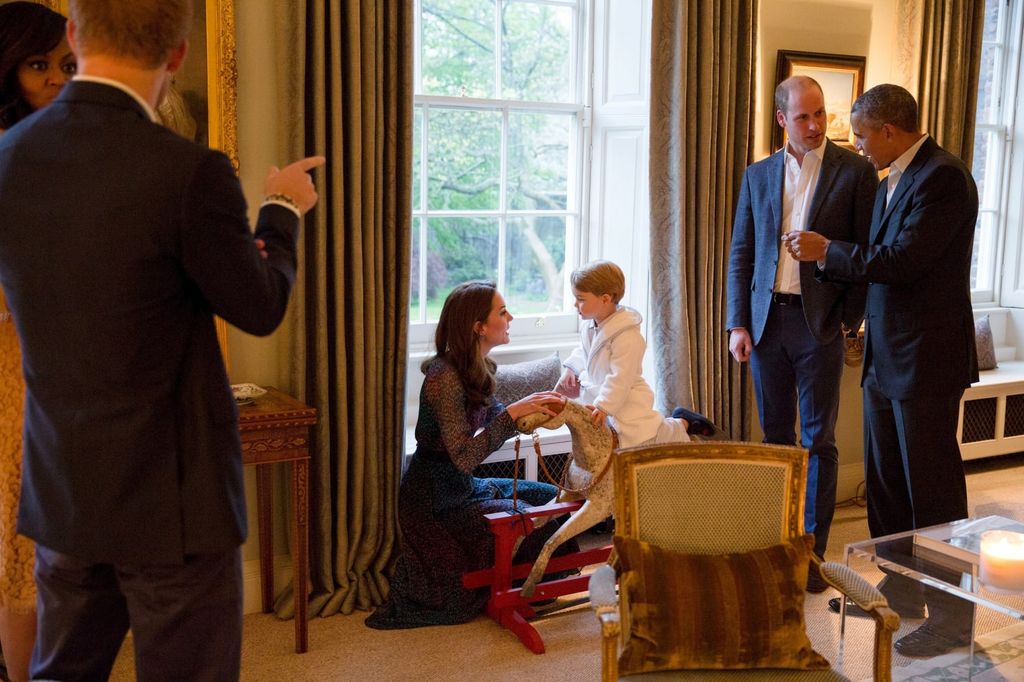 Kate Middleton playing with young Prince George on rocking horse while Barack Obama speaks to Prince William