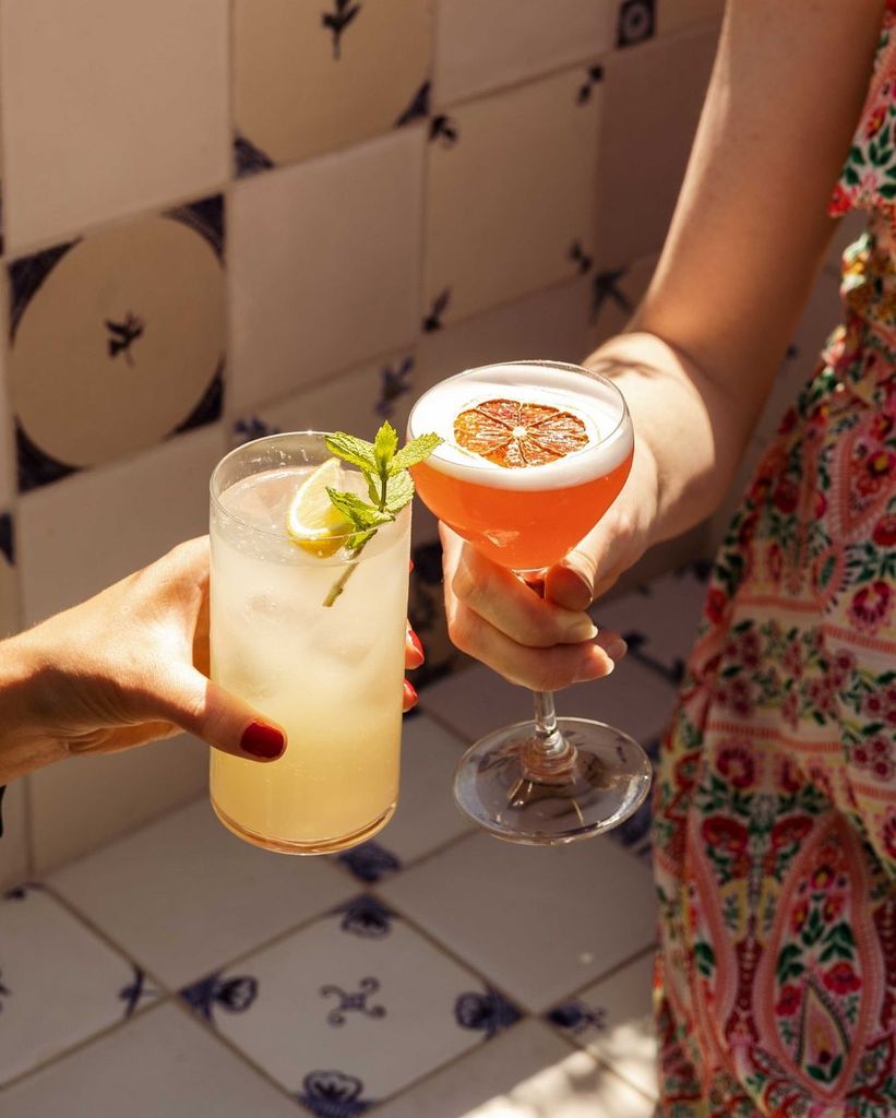 two women cheersing cocktails in the sun