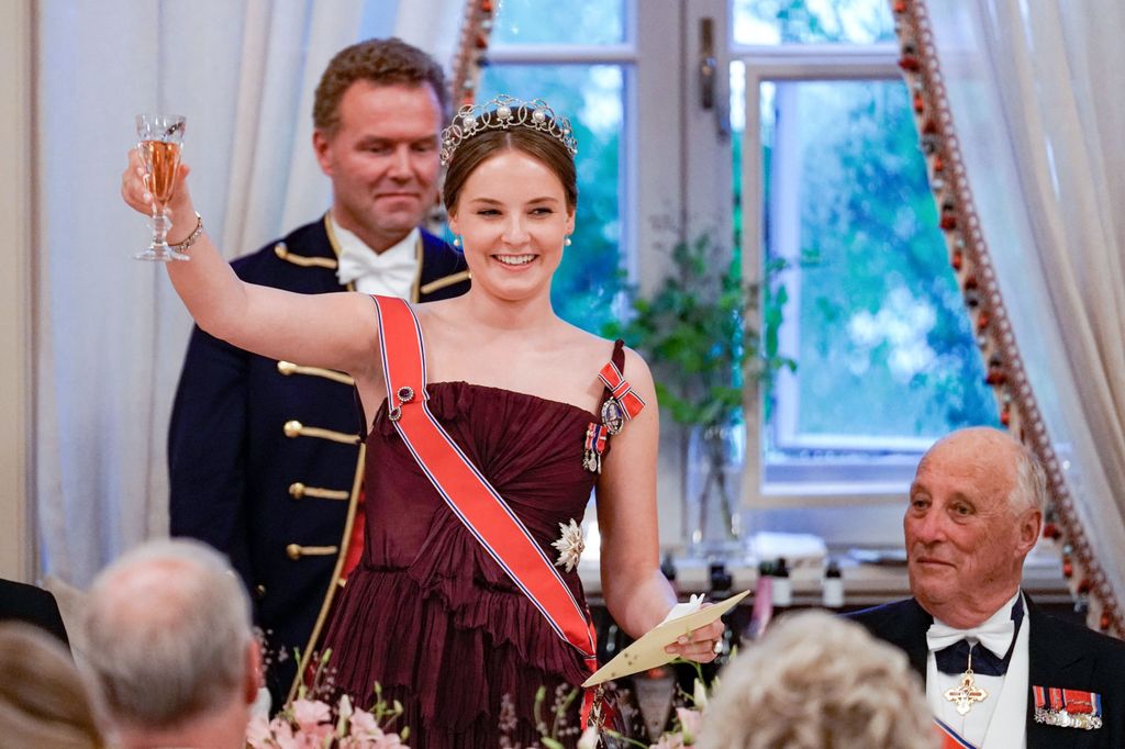 Norway's Princess Ingrid Alexandra (L) raises her glass for a toast next to Norway's King Harald V, as she delivers a speech during a gala dinner for her 18th birthday in Oslo on June 17, 2022.