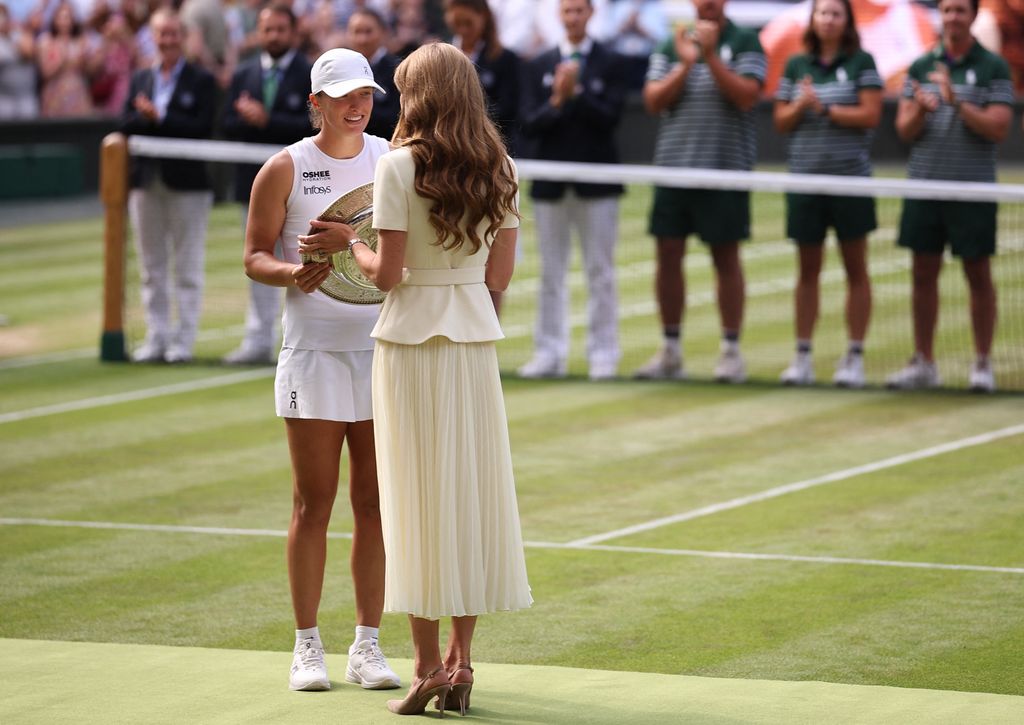 Britain's Catherine, Princess of Wales (R) gives the winner's trophy, the Venus Rosewater Dish, to Poland's Iga Swiatek (L) 