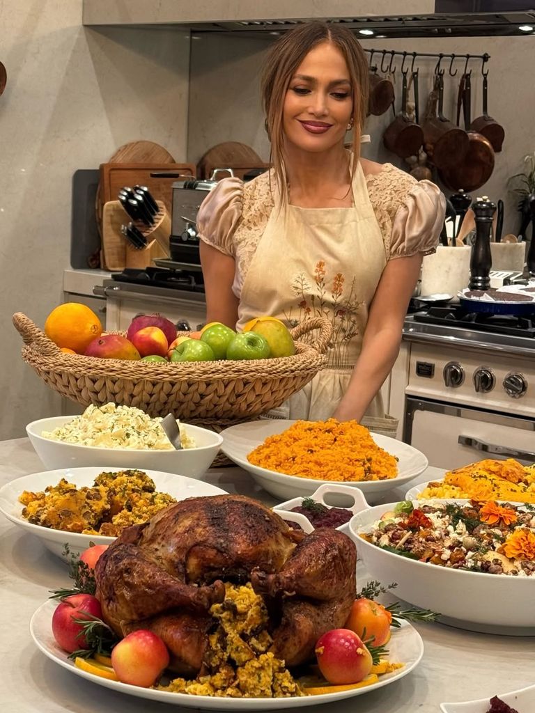 Jennifer Lopez smiling in kitchen next to Thanksgiving spread