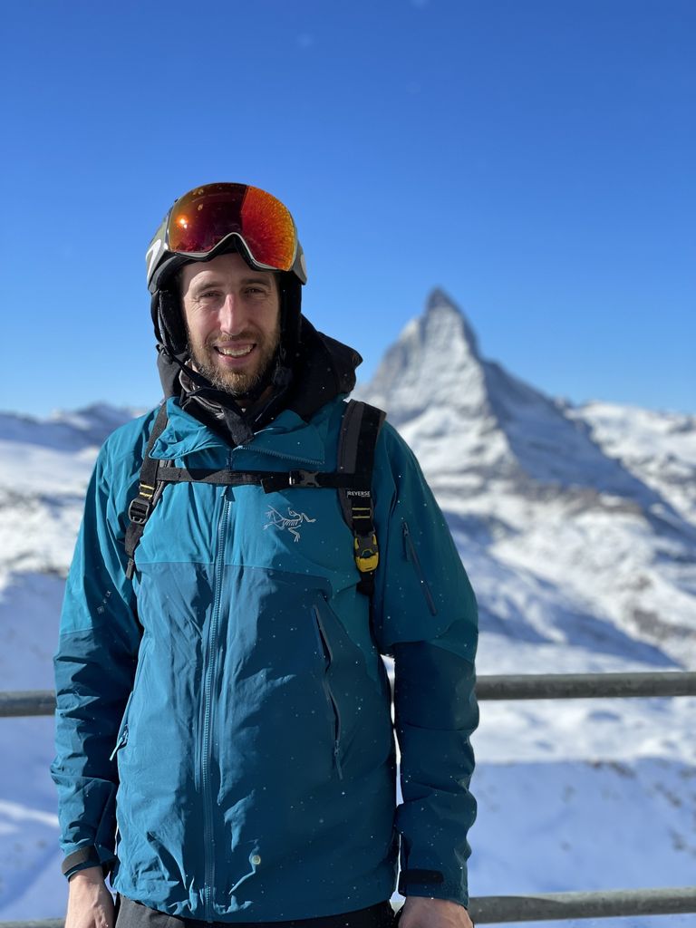Skier smiling in a blue jacket and orange goggles