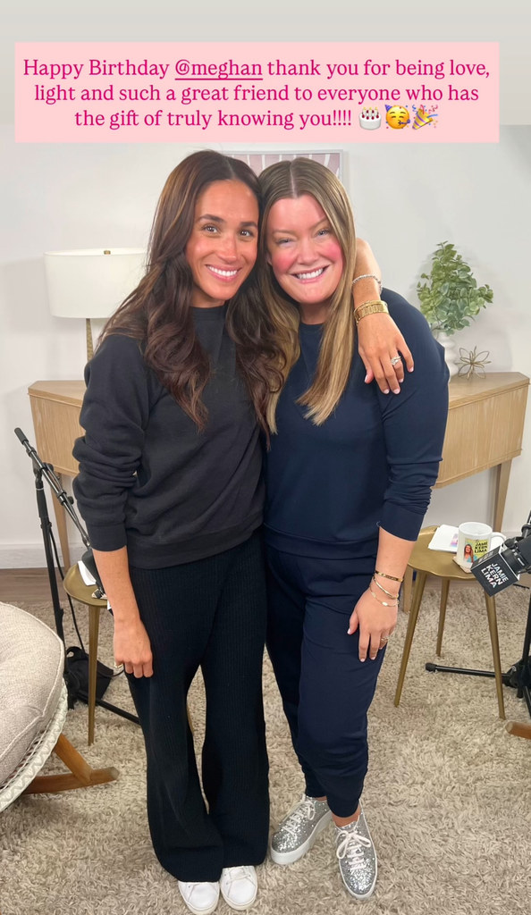 Jamie smiling beside Meghan who has her arm around her