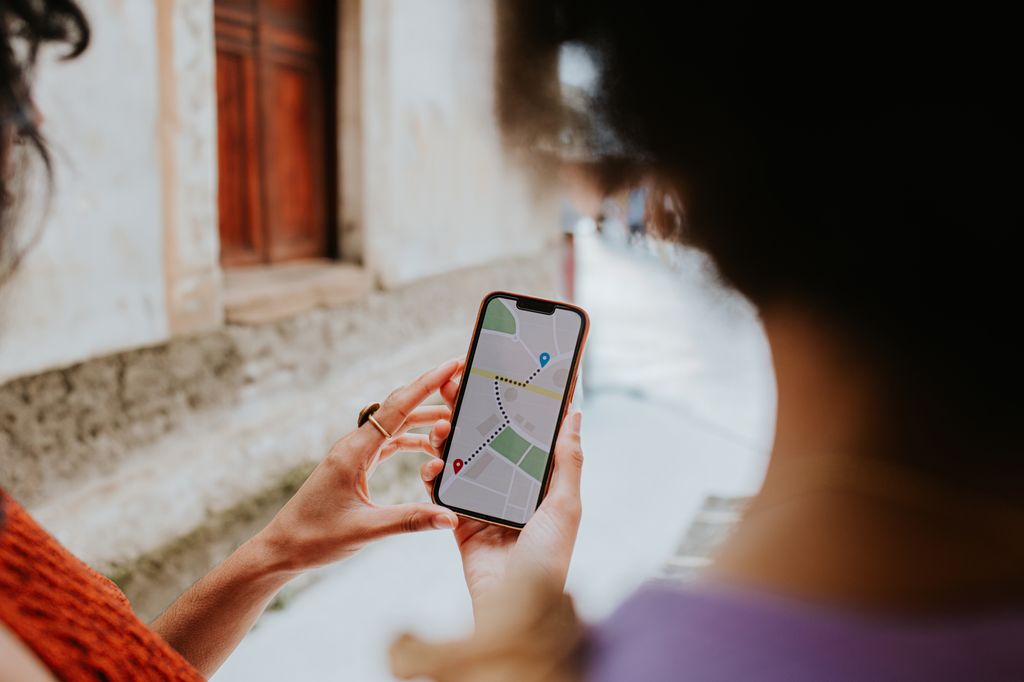 Two woman on vacation use their smart phone, following a map application to their destination.