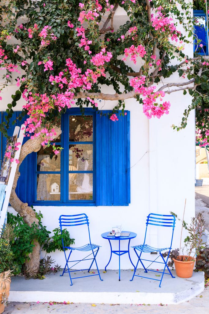 White building with blue shutters and outdoor seating in Mohlos, Eastern Crete