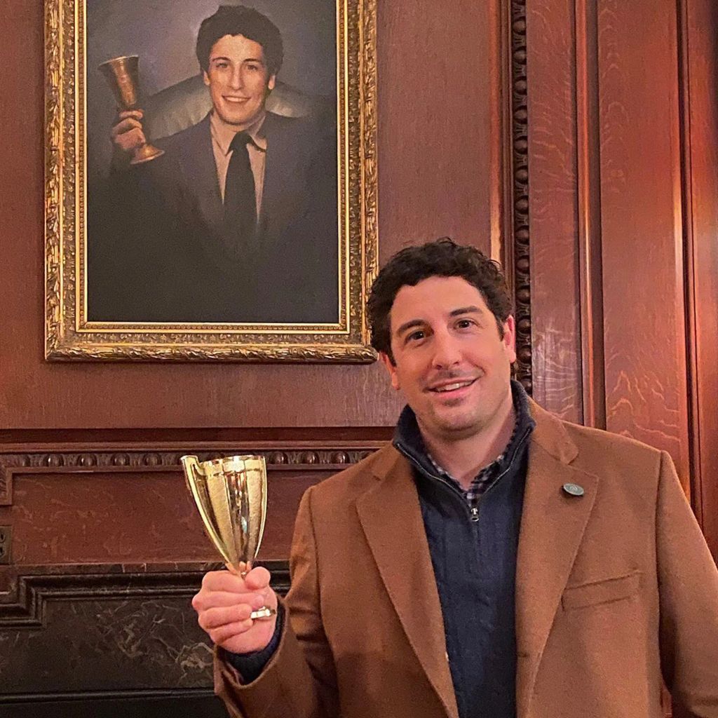Photo shared by Jason Biggs on Instagram of himself in a brown jacket holding a gold cup