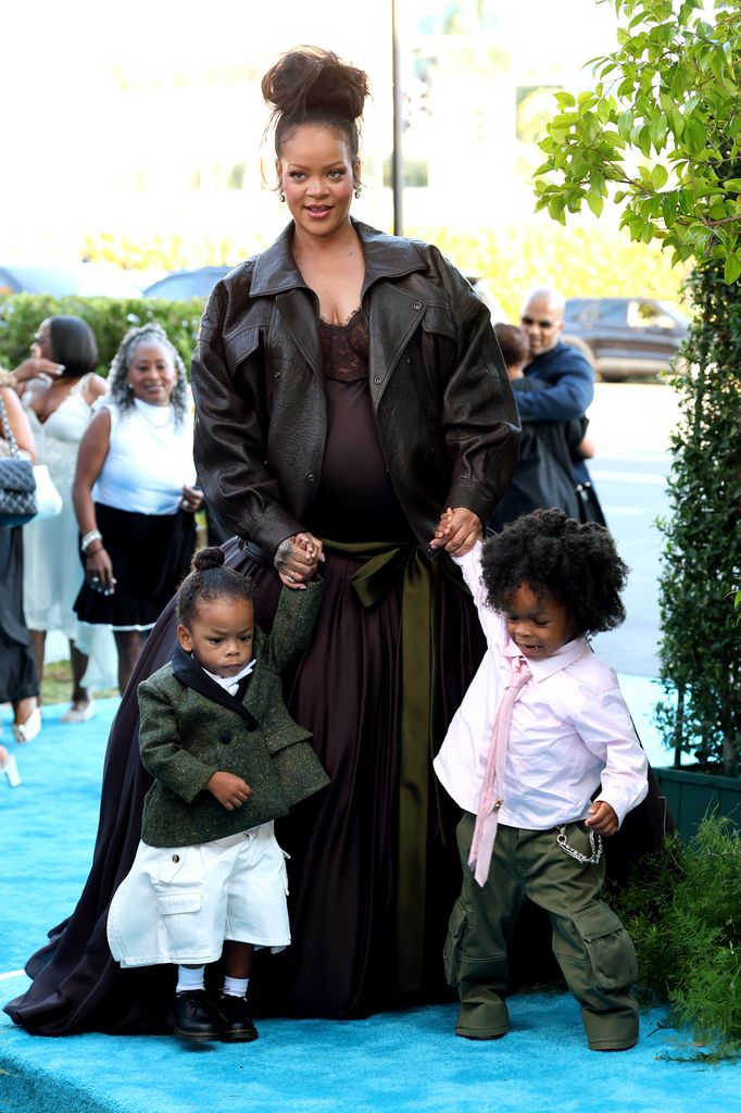 RZA and Riot holding rihanna's hand on blue carpet