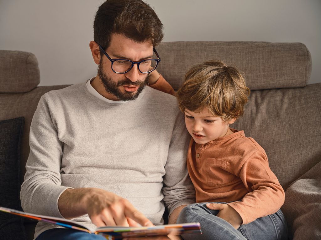 Father reading a story to his son on the sofa