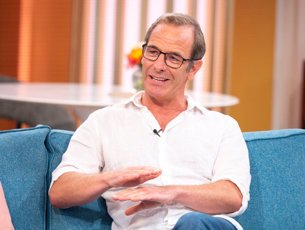 Man in white shirt sitting on blue sofa in tv studio